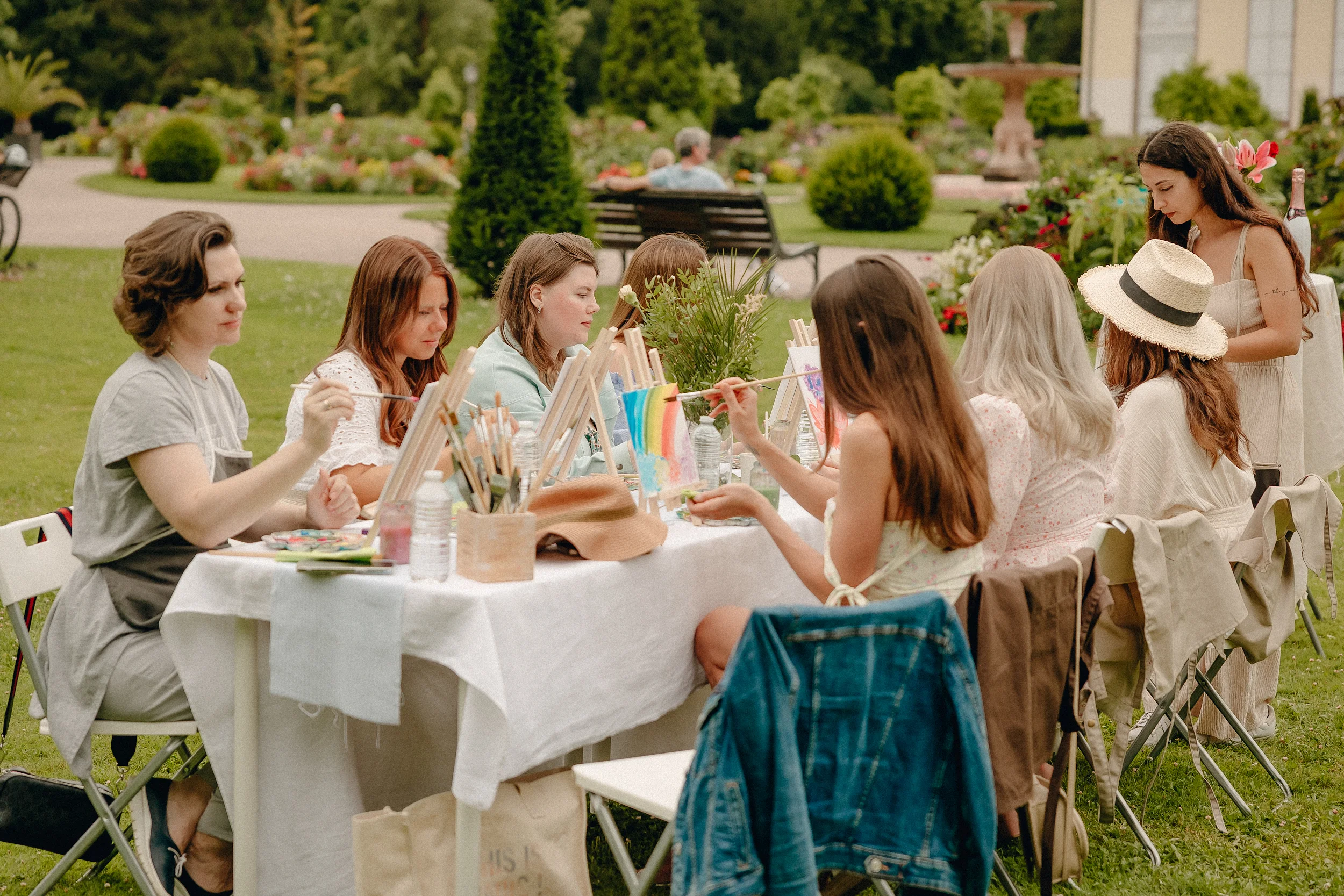 Atelier artistique en extérieur, groupe de femmes peignant ensemble dans un jardin fleuri
